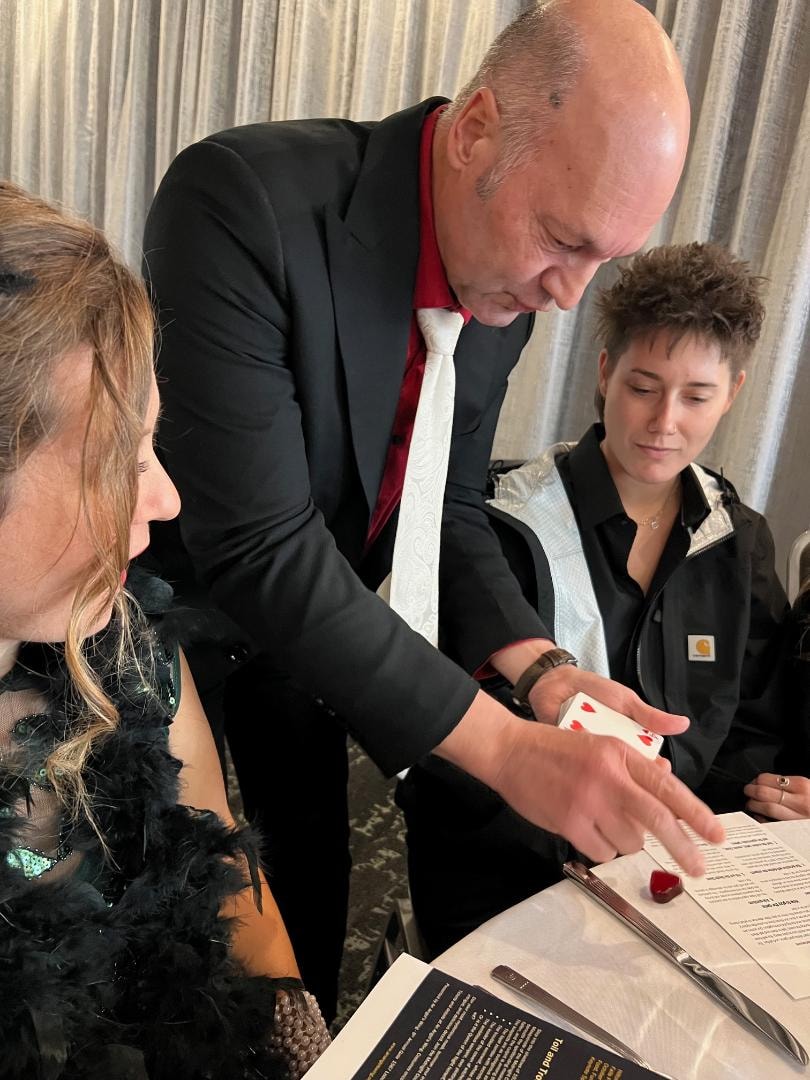Angels Among Us Gala — magician performing card trick at table
